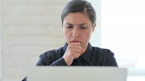 Nahaufnahme einer indischen Frau mit Laptop beim Husten