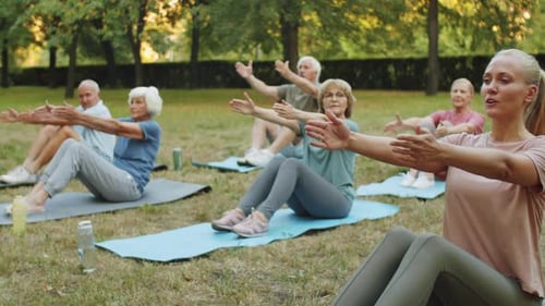 Yoga Teacher and Senior People Exercising in Park