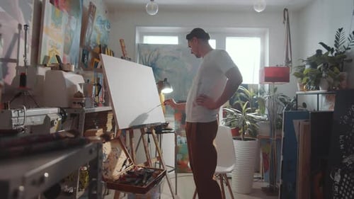Männlicher Künstler zeichnet Bild auf Leinwand im Studio