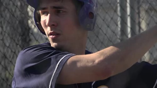 A young man practices baseball at the batting cages.