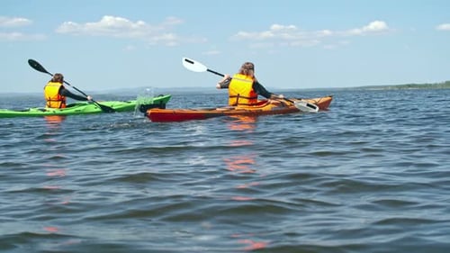 Kayakers Paddling Across Water on a Sunny Day