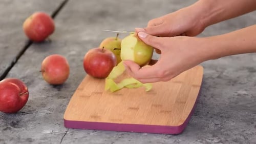 Hands peeling an apple with a knife