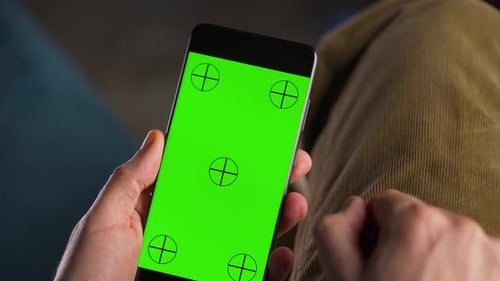 Man Using Smartphone with Green Mockup Screen in Vertical Mode