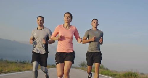 Multiethnic Group of Athletes Running Together on a Panoramic Countryside Road