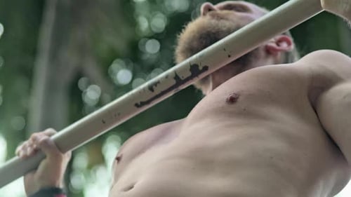Plan d'un homme torse nu faisant le pullup avec une vue de la nature à l'arrière
