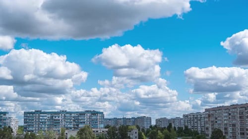 Cumulus Cirrus Clouds Move in the Blue Sky Over Multi-story Buildings in City