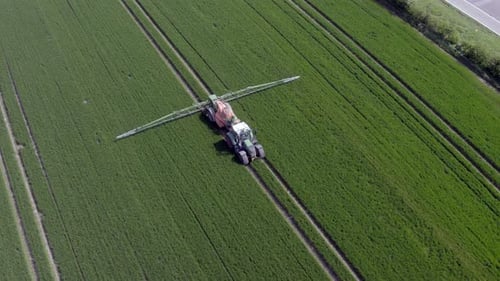 Tractor Spreading Fertilizer on Green Crops