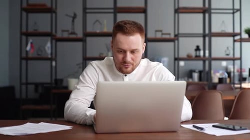 Man Working on Laptop at Desk in Office