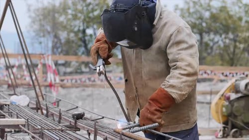 Schweißer auf der Baustelle schweißt Rohr mit Elektrode im Helm
