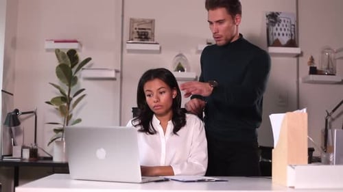 Man and Woman Talking and Using Laptop at Table in Modern Office Spbi