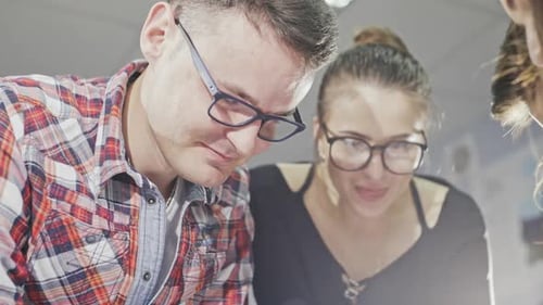 Team Collaborates Over Architectural Blueprints in Workplace