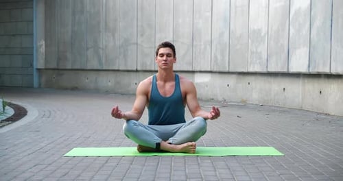Man Meditating on Yoga Mat Outdoors in Urban Setting