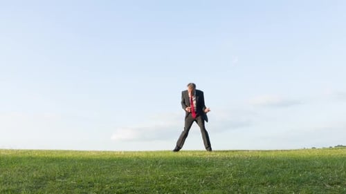 Man Plays Air Guitar in Grassy Field