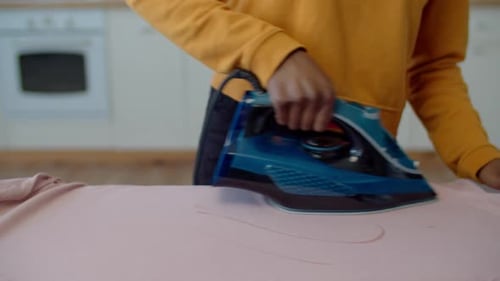 Closeup of Female Hand Ironing Clothes with Electric Iron
