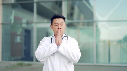 portrait stressful Asian doctor sitting or standing outside a hospital