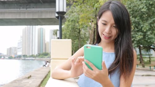 Young Woman Uses Smartphone by City Riverfront