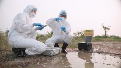 Two Ecologist full in PPE took a sample of water in toxic area to check contaminants.
