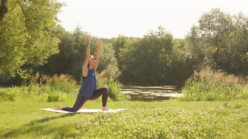Young athletic woman practicing yoga pose in park at sunrise.