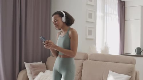 Woman Dancing with Headphones and Smartphone at Home