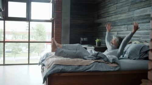 Mature Man Jumps on Bed in Bedroom