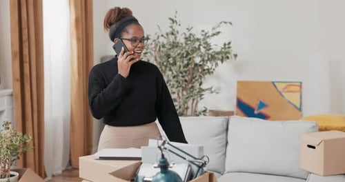 Woman Talks on Phone Amid Moving Boxes