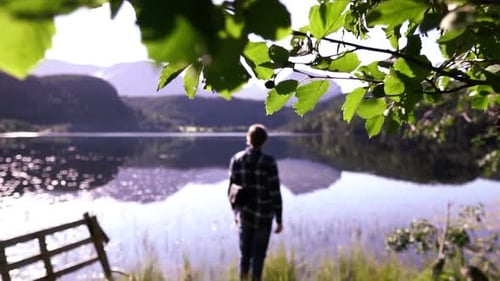 Man standing at a beautiful lake, thinking, enjoying and relaxing after a long hike, breathing in li