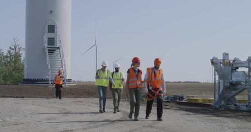 Grupo de trabajadores que se alejan de una turbina eólica