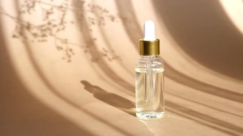 Dropper Bottle of Serum on Tan Surface