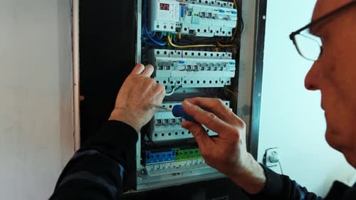 Man Repairing Electrical Panel with Screwdriver