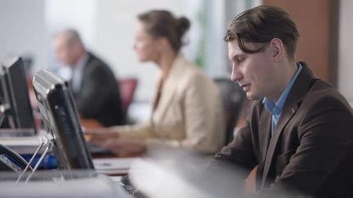 Workers Typing at Computers in a Bright Office