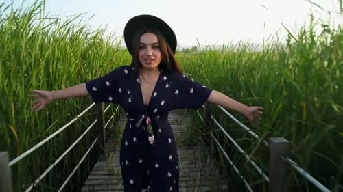 Stylish Woman Walks Wooden Bridge in Green Marshland