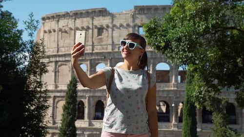 Smiling Woman Takes Selfie in Front of Colosseum