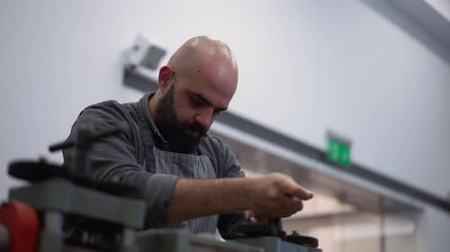 Confident Bearded Man Spinning Handle on Equipment in Jewellery Workshop in Slow Motion