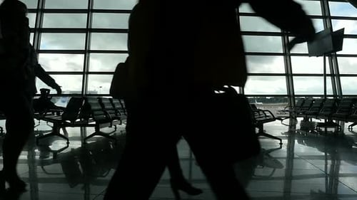 Reisende gehen am Fenster im Flughafenterminal entlang, Menschen Silhouetten zu Fuß.