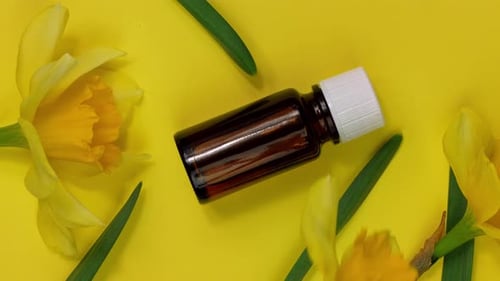 Amber Bottle with Daffodils on Yellow Background