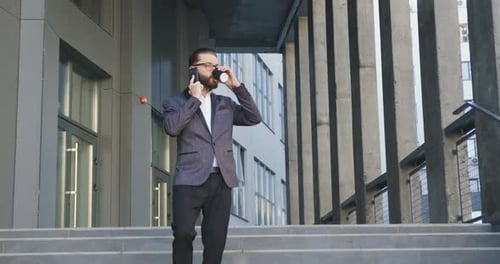 Office Worker in Glasses and Stylish Suit which Drinking Coffee and Talking on Phone