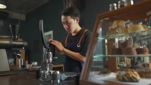 Young Adult Barista Making Coffee with Manual Machine