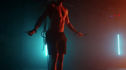Muskulöser Mann mit nacktem Torso springt mit einem Springseil
