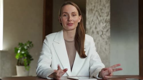 Businesswoman Talking at Desk with Tablet