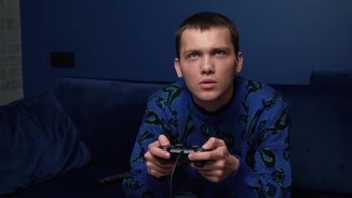 Front View of an Excited Emotional Caucasian Man Playing Video Games and Using Joystick Controller