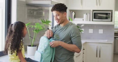 Happy biracial father and daughter packing lunch for school