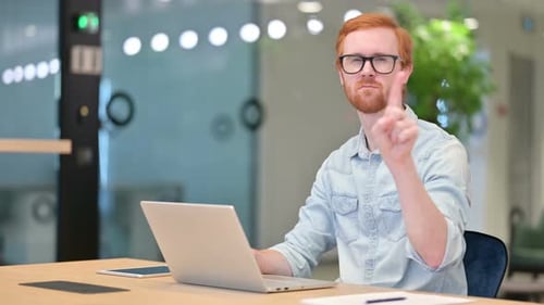 No Sign By Casual Redhead Man Working on Laptop in Office