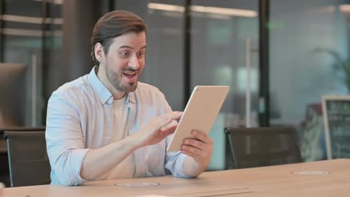 Man Celebrating Success While Using a Tablet