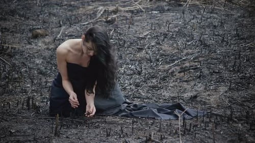 Woman Kneeling in Burnt Field, Black Fabric, Barren