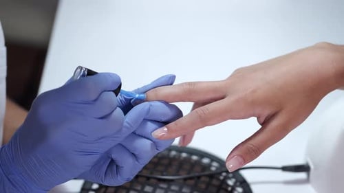 Close-up of Beautician Hands Making Blue Manicure for Client
