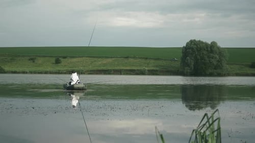 Mann im Boot beim Angeln mit Angelrute. Fischer fängt Fische am See. Angeln am See.