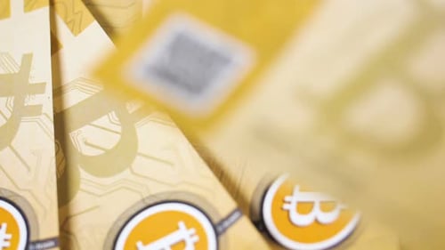 Les bitcoins en papier s'envolent sur une pile de