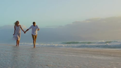 Couple walking together on beach during sunset