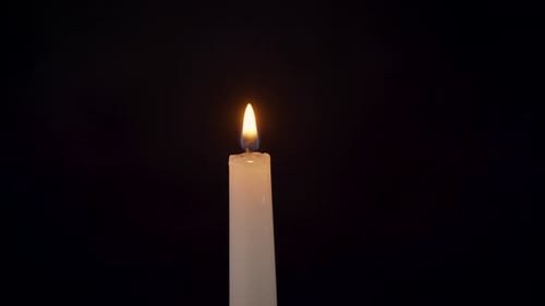 Gros plan d'une bougie allumée isolée sur fond noir