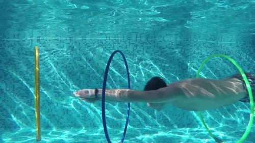 Man Swimming Through Rings in the Pool
